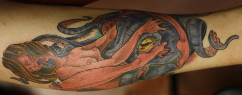 tattooed arm with purple octopus and nude girl
