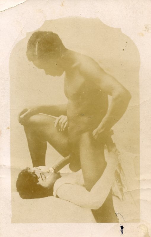 Vintage interracial old photograph with a white woman sucking a black male