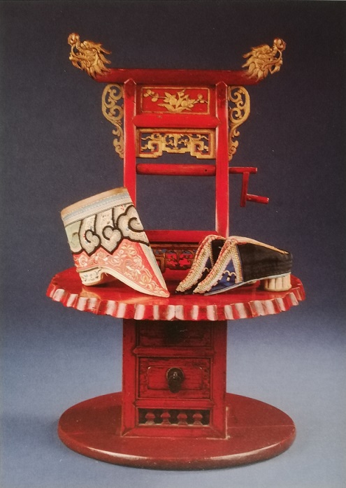 Red lacquer and gilt wooden footbinder's chair with three lotus shoes on it<