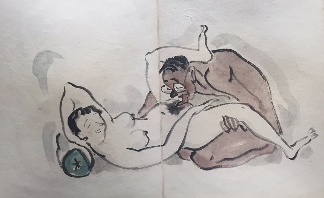 'Completely nude male wearing glasses performing cunnilingus on a nude female leaning back on a geisha pillow'